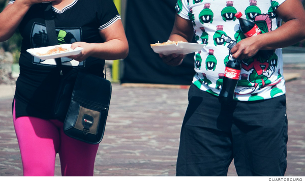 Fotografía de dos personas comiendo comida chatarra y alimentos ultraprocesados que producen obesidad