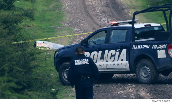 Imagen de un policia de frente a su patrulla investigando homicidios