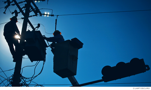 Trabajadores cerca de generadores de energía sobre un poste