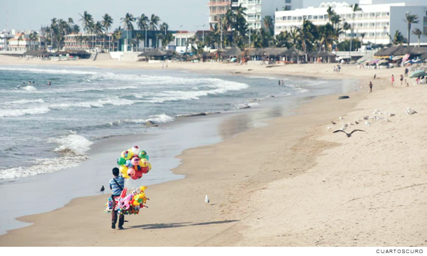 Fotografia de un vendedor de globos caminando por la playa