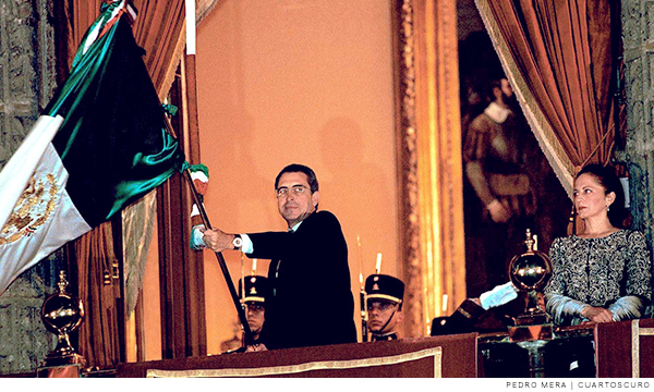 El expresidente de México, Ernesto Zedillo Ponce de León, ondea la bandera del país desde el balcón de palacio nacional