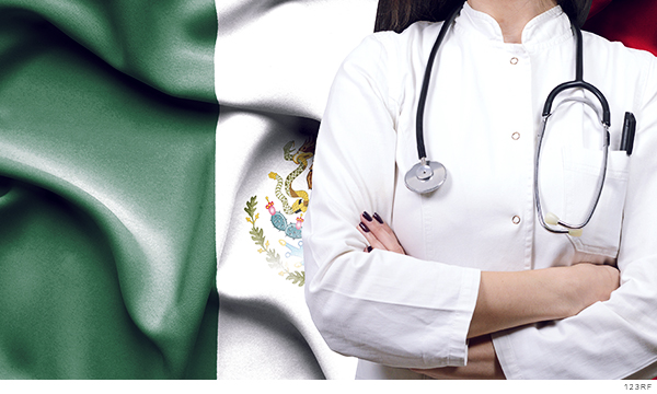 Fotografía del torso de una doctora, al fondo la bandera de México